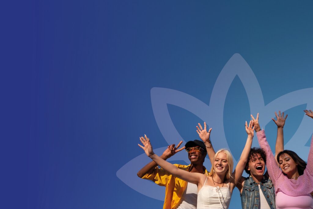 A diverse group of young adults in colourful clothing waiving their arms towards the sky.