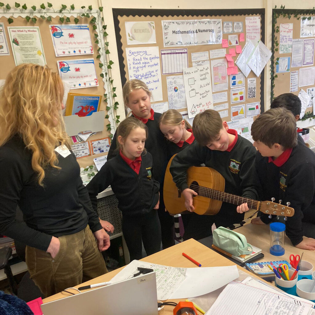 Young and Mindful during classroom mindfulness session. The pupils are listening contently as another student plays the acoustic guitar.