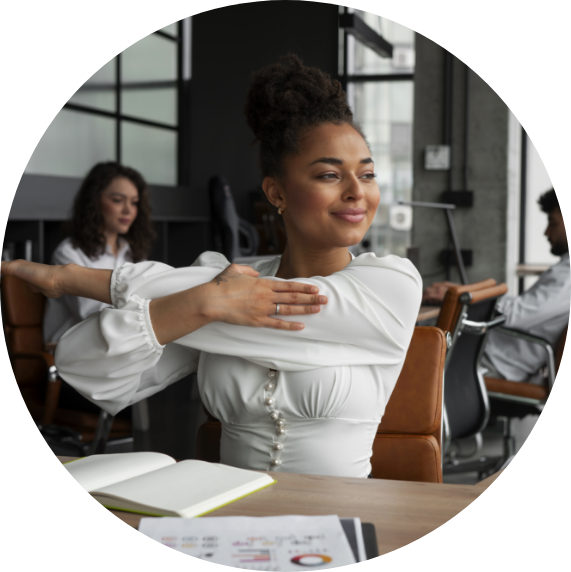 A employee in a corporate setting, sat at her desk stretching her arms