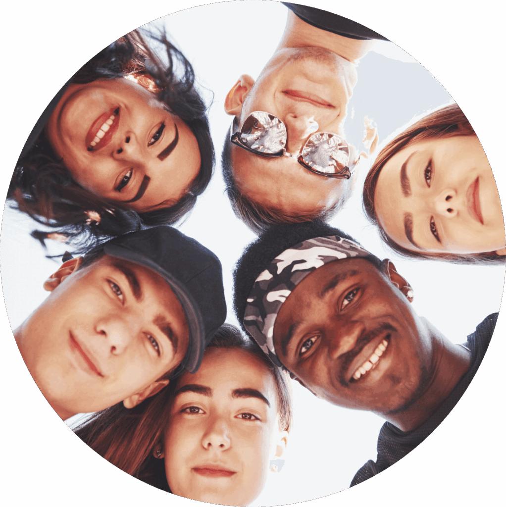 Six teenagers with their heads in a circle, looking down smiling at the camera below them