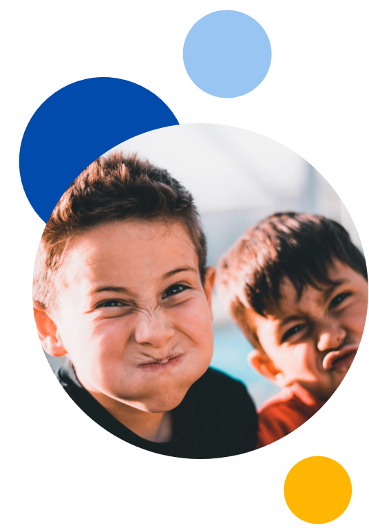 Two young boys pulling funny faces at the camera in a circle with blue, yellow and light blur circles surrounding them.